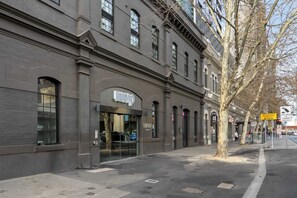 Un edificio con vetrine, ampie finestre e una strada alberata.