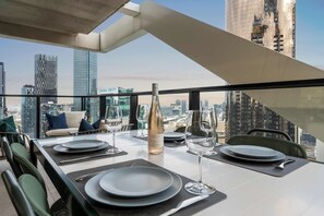 Zona pranzo sul tetto con vista sulla città, una bottiglia di vino e un tavolo apparecchiato per due persone.