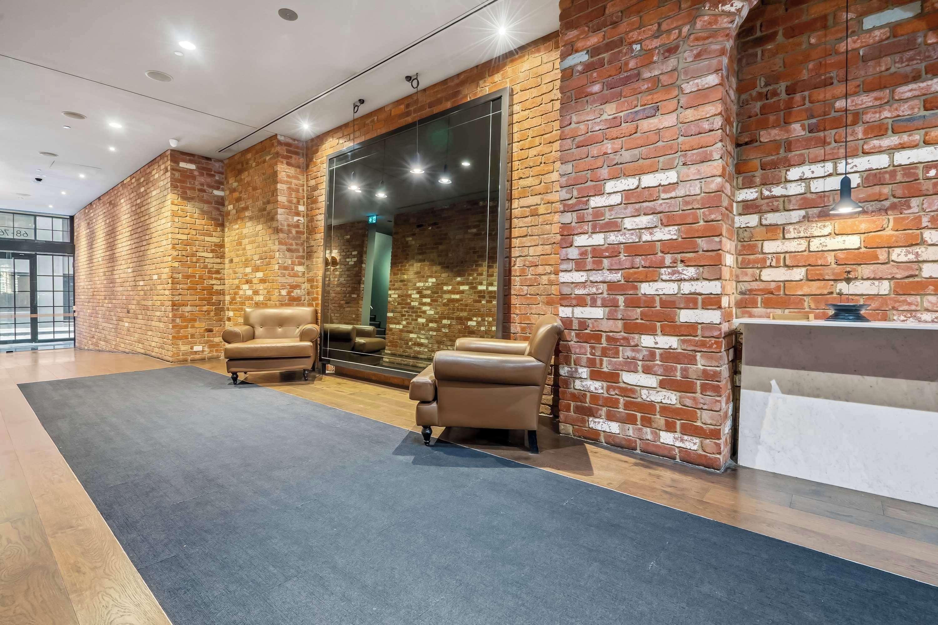 A modern lobby with brick walls, leather sofas, and a reception desk.