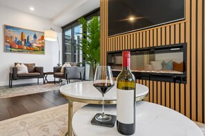 A modern living room with a round table, a wine bottle, and a glass of red wine. - 36th Floor Luxury 3BR  City Views Pool & 2 Cars (Southbank)