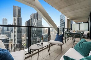 Un appartamento alto con un balcone, arredato con un tavolo, sedie e un divano.