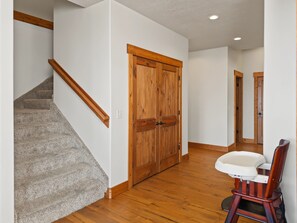 A hallway with a wooden staircase, a double door, and a baby changing station.