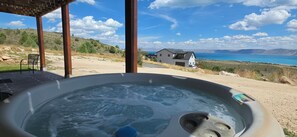 A hot tub with a view of a house and a body of water.