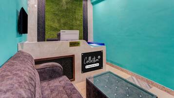 Zona de recepción con mostrador, pared verde, candelabro y área de piscina.