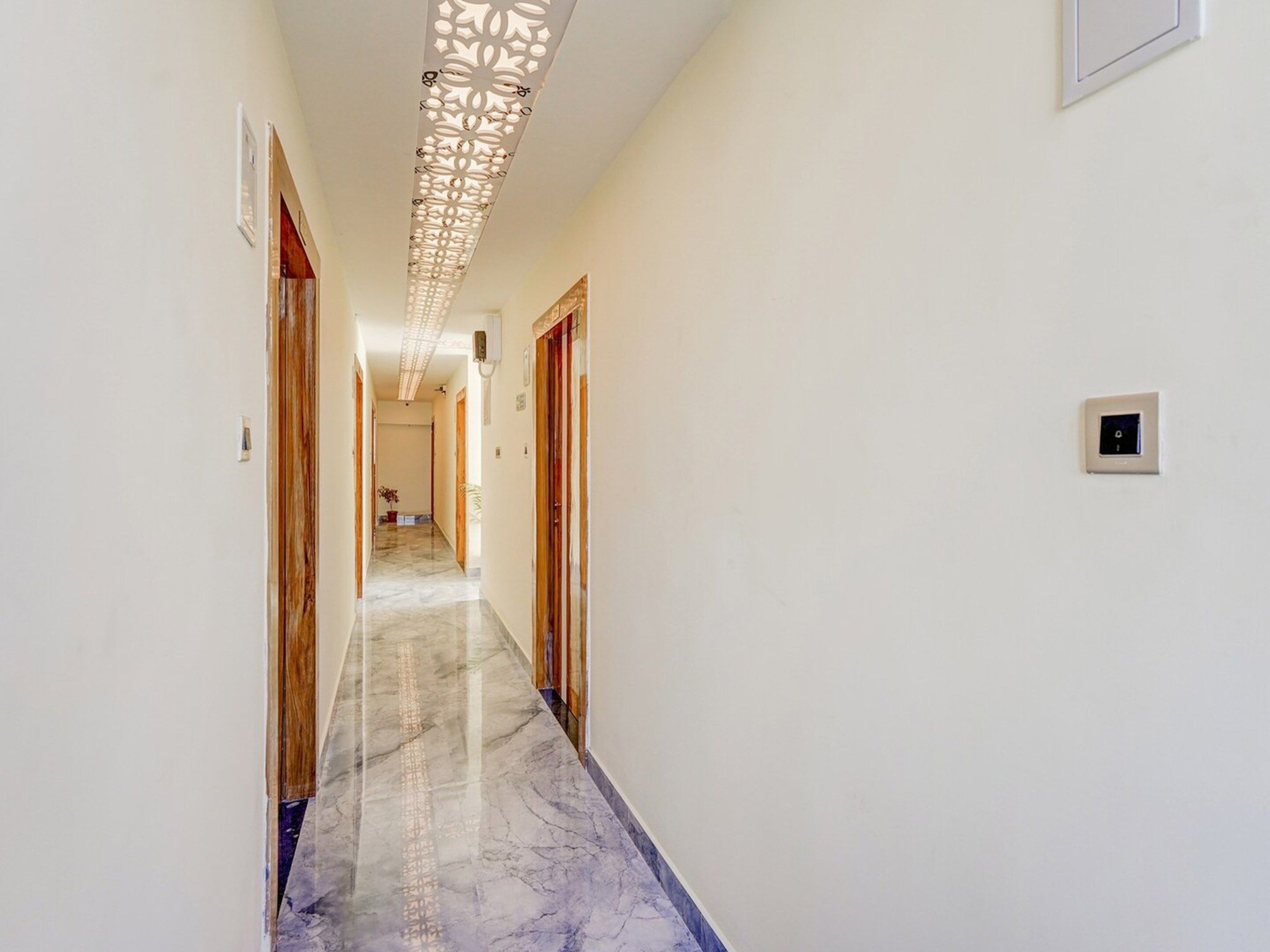 A hallway with a marble floor, wooden doors, and a decorative ceiling panel.