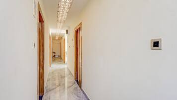 A hallway with a marble floor, wooden doors, and a decorative ceiling panel.