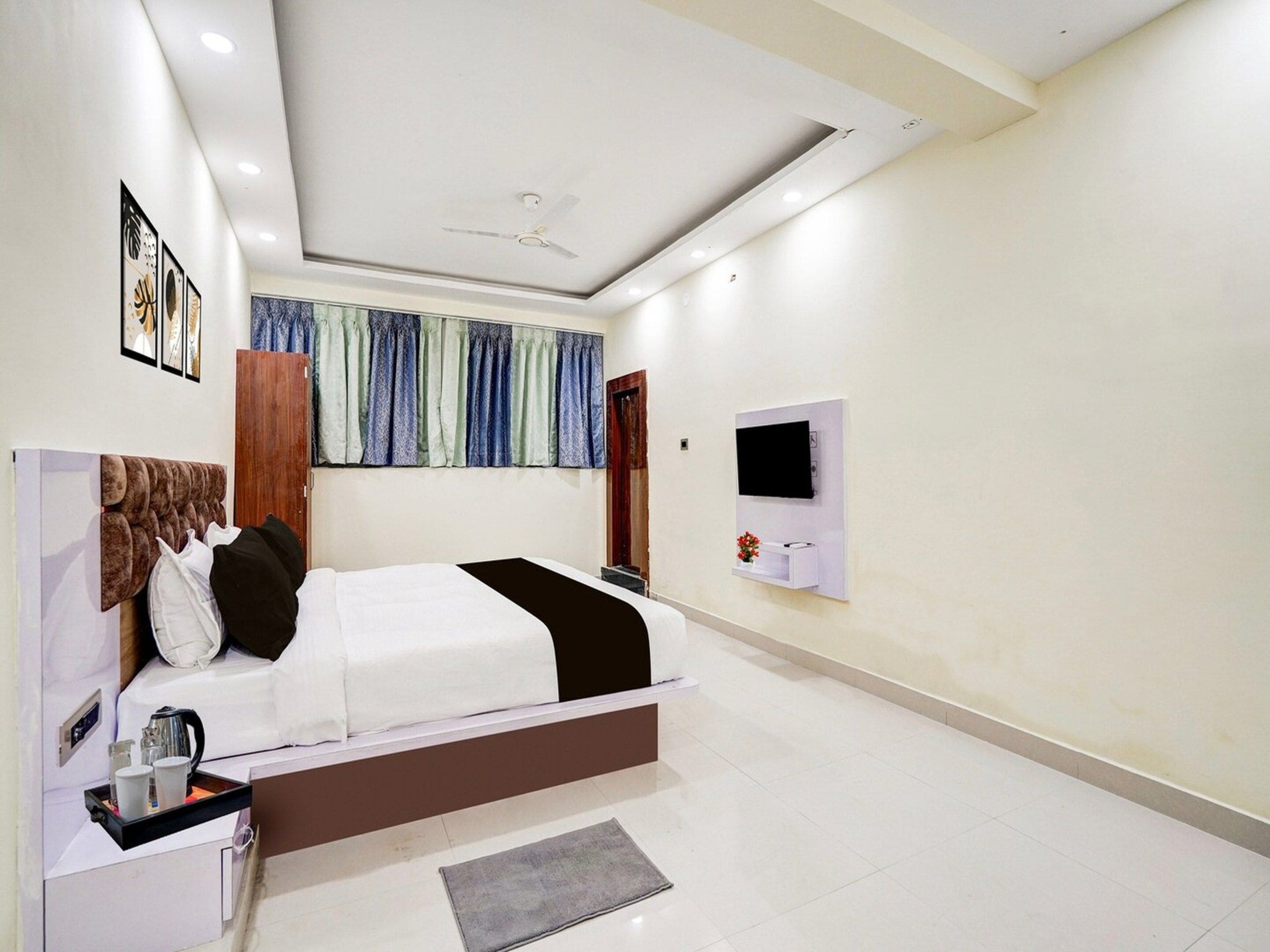 Un dormitorio moderno con una cama grande, un televisor de pantalla plana montado en la pared y un ventilador de techo.