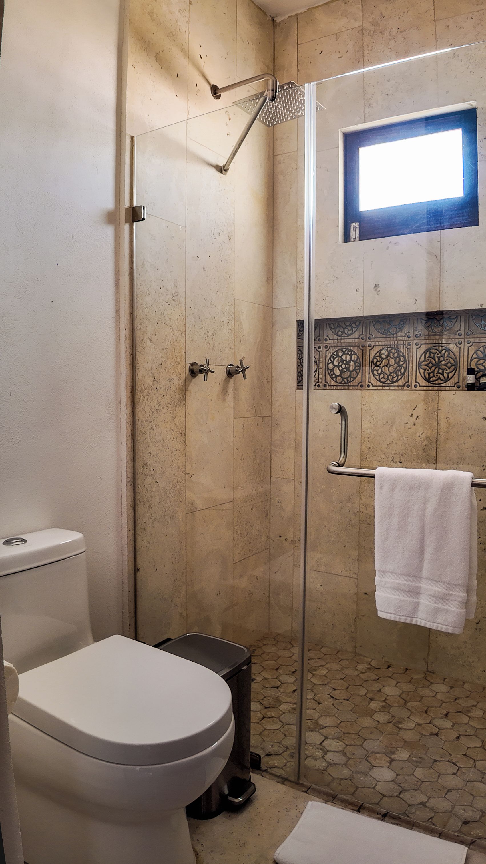 Un baño con ducha de vidrio, inodoro y lavabo.