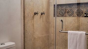 Un baño con ducha de vidrio, inodoro y lavabo.