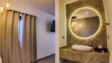 Un baño con espejo redondo, lavamanos y zona de ducha.