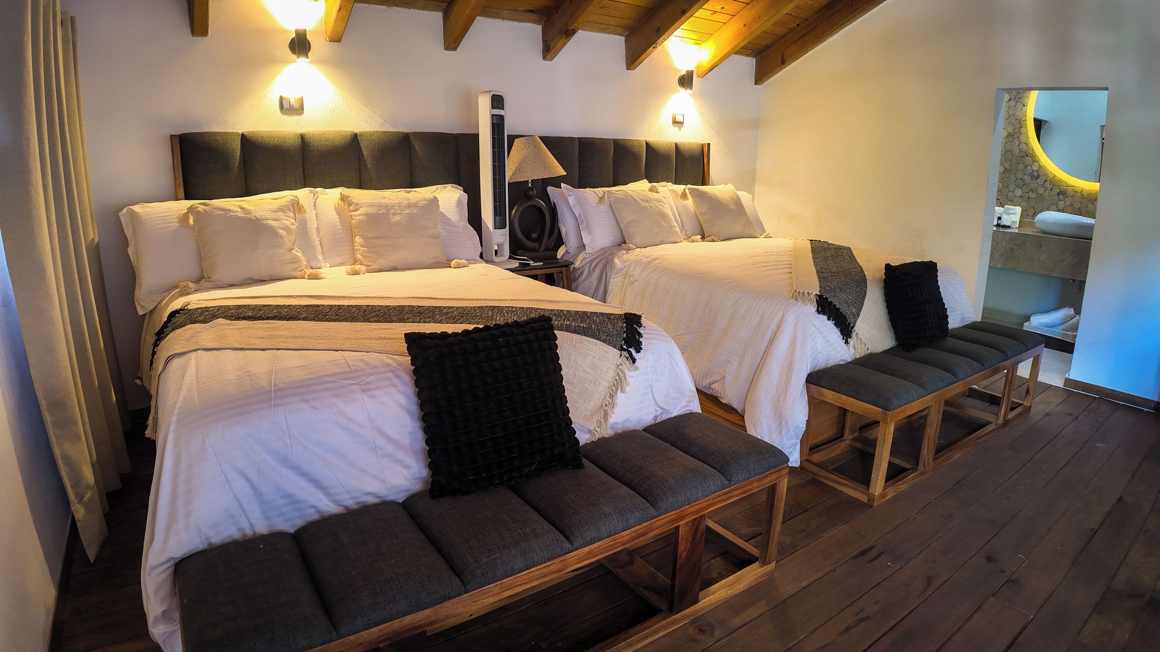 A double bed with a headboard, bedside tables, a bench, and a mirror.