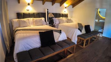 A double bed with a headboard, bedside tables, a bench, and a mirror.