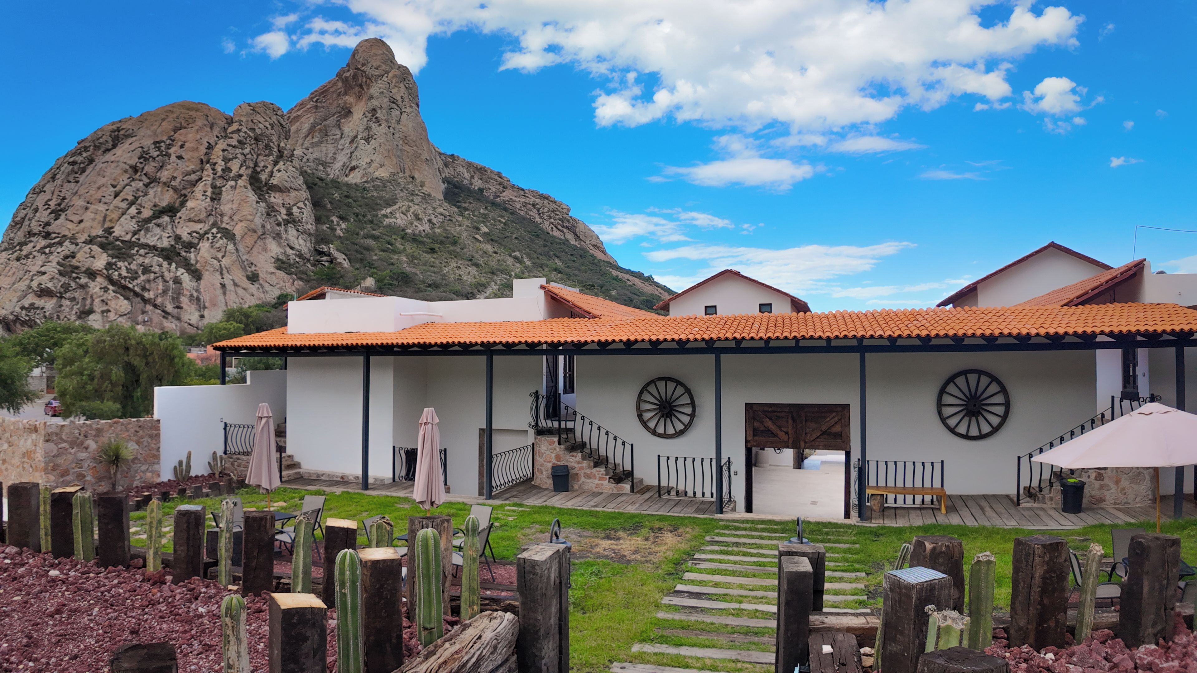 Un edificio con techo de tejas, una escalera que lleva a una puerta y una montaña al fondo.