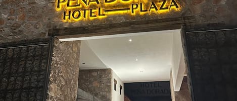 La entrada al Hotel Pena Dorada Plaza, con fachada de piedra y una escalera que conduce al interior.