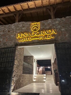 La entrada al Hotel Pena Dorada Plaza, con fachada de piedra y una escalera que conduce al interior.