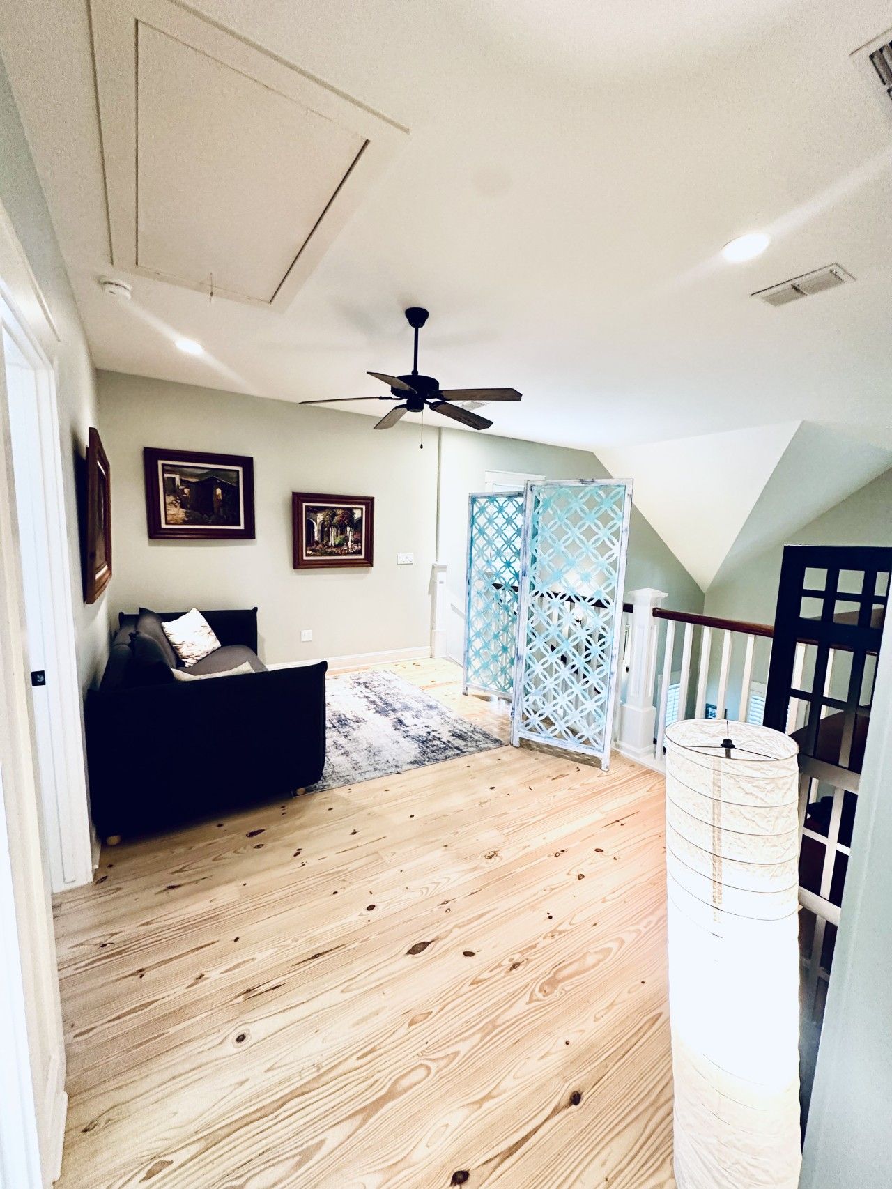 A room with a ceiling fan, a bed, a sofa, and a staircase leading to an upper level.
