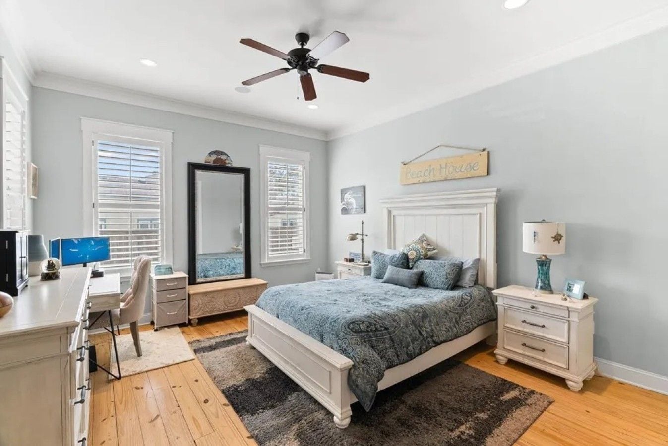 A bedroom with a bed, desk, chair, and a ceiling fan.