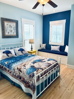 A bedroom with a bed, a window seat, a ceiling fan, and a framed picture on the wall. - Where the Boardwalk meets the Bay! (Rockport)