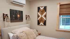 Une chambre à coucher comprenant un lit, une fenêtre, un climatiseur fixé au mur et deux lanternes fixées au mur.
