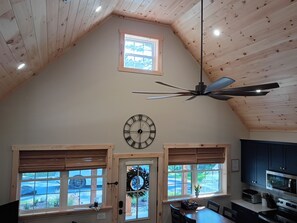 Eine geräumige Küche mit modernem Design, inklusive einer großen Uhr, einem Deckenventilator und Blick durch die Fenster.