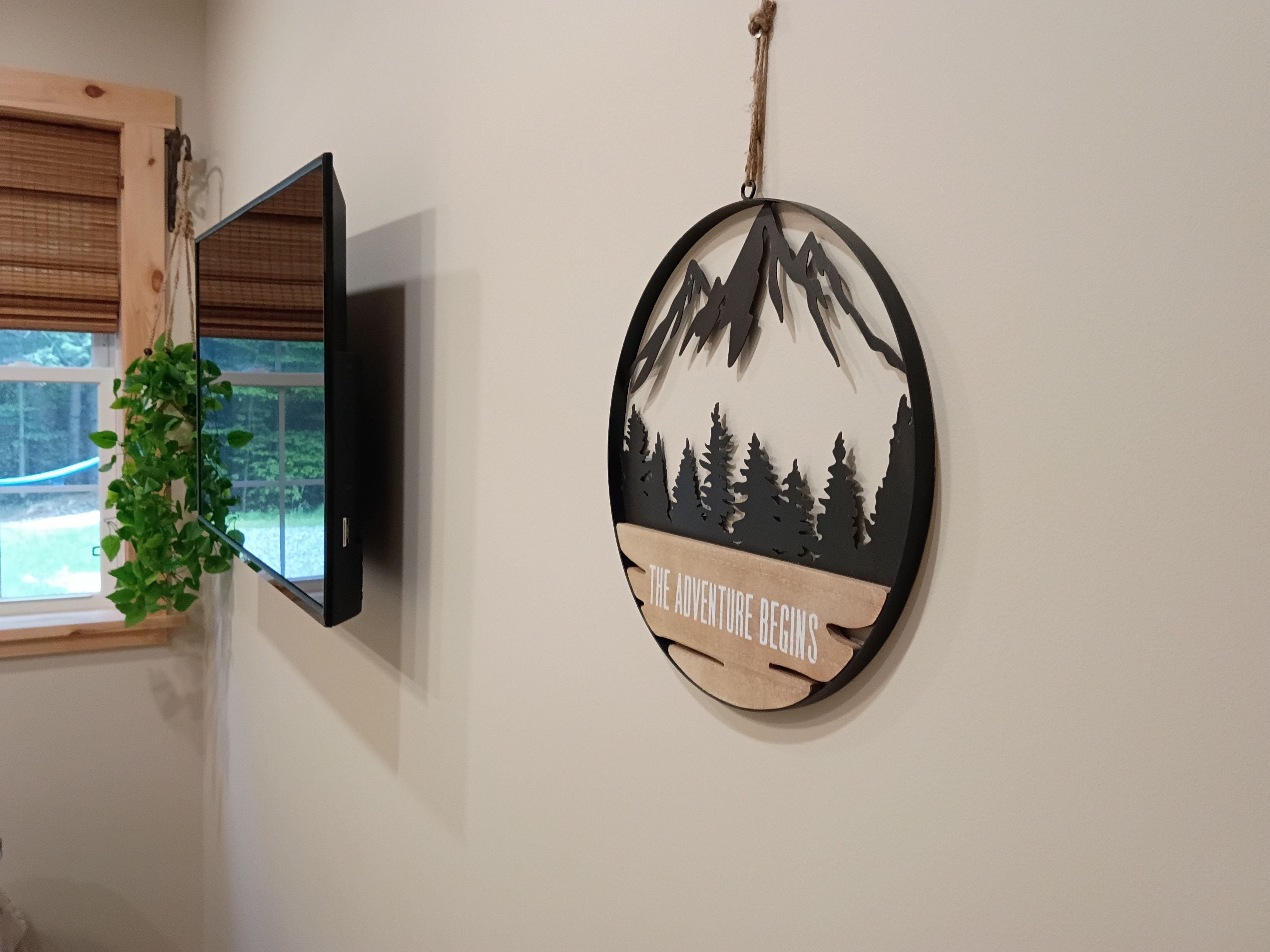 A flat-screen TV mounted on a wall with a window to the left.