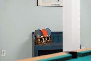 Een kamer met een blauwe muur, een lijst met een afbeelding en een rek met tafeltennisrackets.