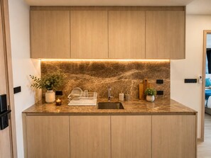 A modern kitchen with a marble countertop, wooden cabinets, and under-cabinet lighting. - 1BR Felix Suite Bangtao Beach (Tambon Choeng Thale)