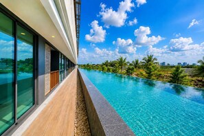 A modern hotel with a long swimming pool, large windows, and a view of the city skyline. - 1BR Felix Suite Bangtao Beach (Tambon Choeng Thale)