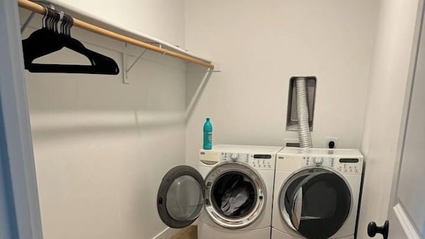 Une buanderie équipée de deux machines à laver à chargement frontal et d’un sèche-linge, ainsi que d’un étendoir et d’une bouteille de lessive.