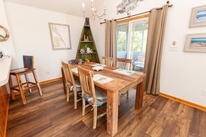A dining area with a wooden table and chairs, a chandelier, and a view through a glass door. - Oceanside, Priv Pool, Hot Tub, comm amenities - VOH1277, Beach Mode (Corolla)