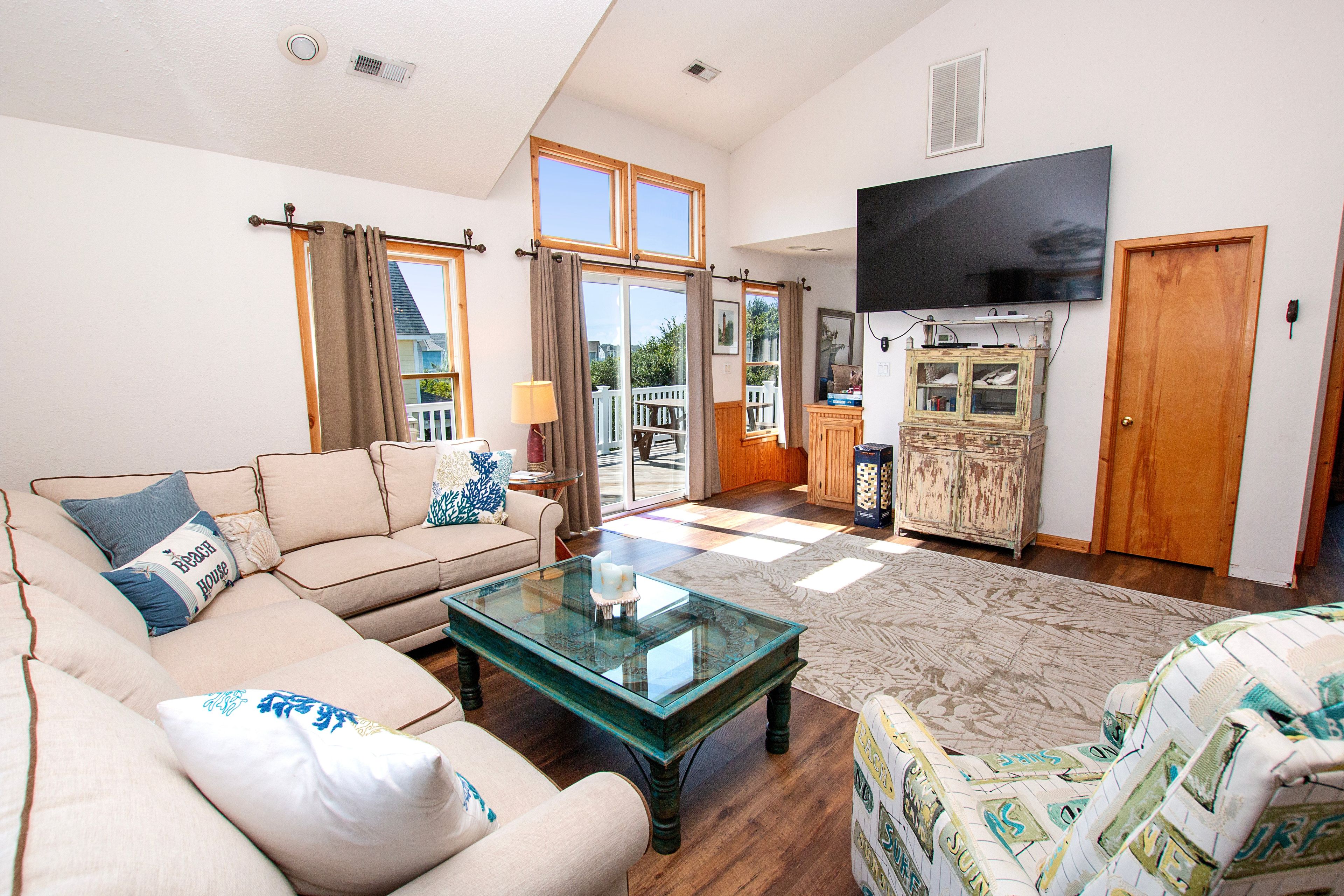 A living room with a sofa, a glass coffee table, and a television mounted on the wall.