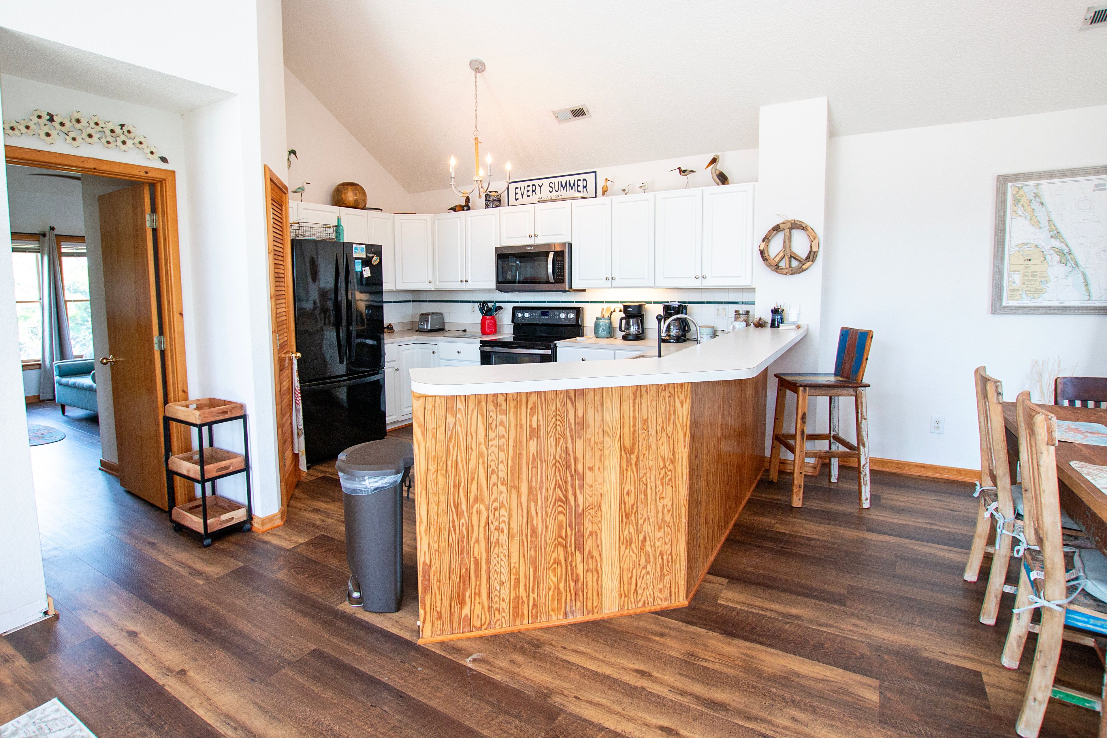 Une cuisine moderne avec des meubles blancs, un îlot central en bois et un coin repas comprenant une table et des chaises en bois.
