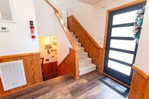 A wooden staircase leading to a second floor, a door with a window, and a wall-mounted fire extinguisher. - Oceanside, Priv Pool, Hot Tub, comm amenities - VOH1277, Beach Mode (Corolla)