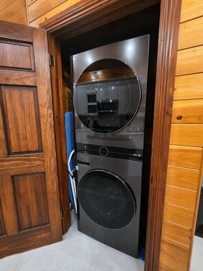 A compact, modern laundry room with a built-in washer and dryer, a microwave, and a small cabinet. - Amazing Oceanfront Condo w Onsite Diving and Restaurant (West Bay)