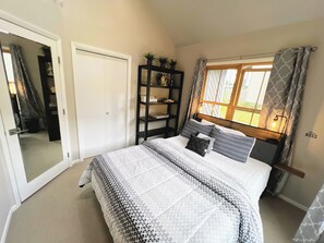 A bedroom with a bed, a wardrobe, a shelf unit, and a window with curtains. - Luxury Home with a River View, Private Hot Tub, and Expansive Deck! (Glenwood Springs)