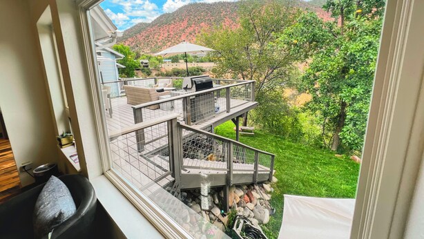 Una terraza con mobiliario exterior, una parrilla y vistas a una colina.