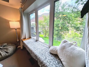 A room with a large window, a bench, a lamp, and a plush toy. - Luxury Home with a River View, Private Hot Tub, and Expansive Deck! (Glenwood Springs)