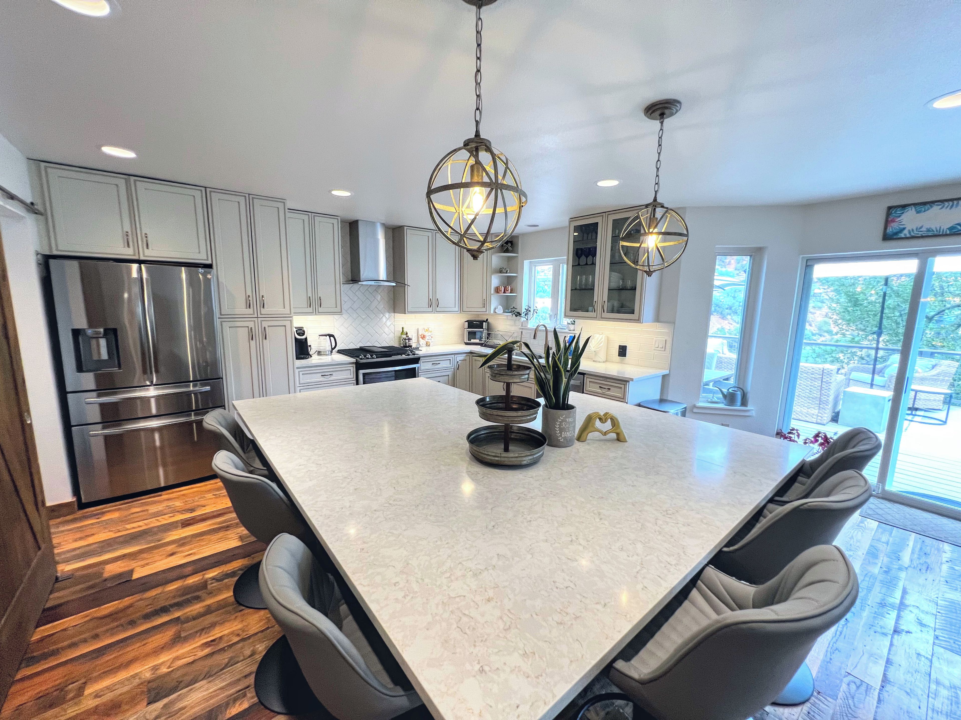 A modern kitchen with a central island, stainless steel appliances, and pendant lighting.