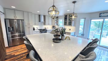 A modern kitchen with a central island, stainless steel appliances, and pendant lighting.