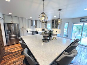 A modern kitchen with a central island, stainless steel appliances, and pendant lighting. - Luxury Home with a River View, Private Hot Tub, and Expansive Deck! (Glenwood Springs)
