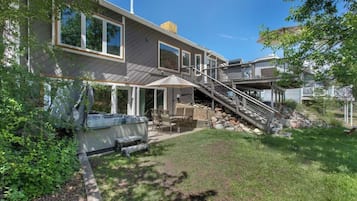 A two-story house with a patio, outdoor seating, and a staircase leading to a deck.