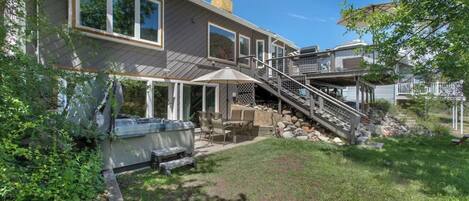 Ein zweistöckiges Haus mit Terrasse, Sitzgelegenheiten im Freien und einer Treppe zu einer Außengaststätte.