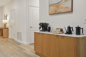 Ett modernt kök med en bänkskiva i trä, kaffebryggare, vattenkokare och tekanna.