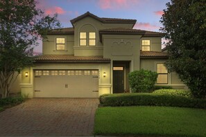 A two-story house with a garage, a front door, and a well-maintained lawn. - Disney Vacation Pool Home | Resort | Game Room (Davenport)