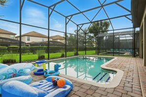 An indoor swimming pool with inflatable toys and a clear view of the surrounding neighborhood. - Disney Vacation Pool Home | Resort | Game Room (Davenport)