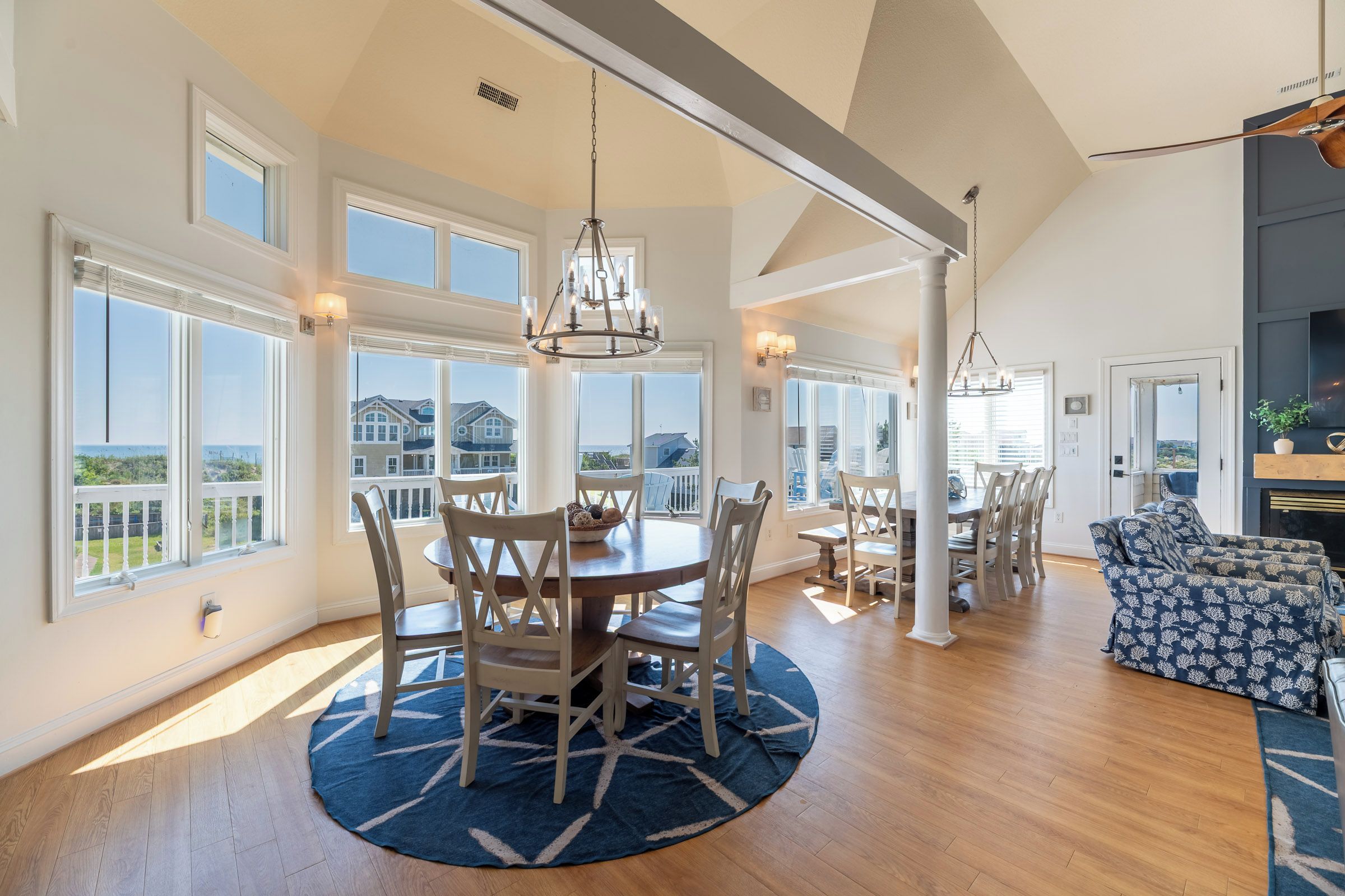 A spacious dining area with a round table, chairs, and a chandelier.