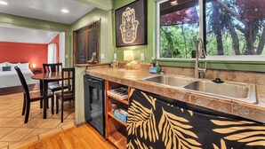 A kitchen with a dining area, a dishwasher, and a window with a view of trees. - Authentic 5-bedroom estate in Kailua-Kona Living in Harmony with nature (Kailua-Kona)