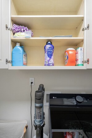 A laundry room with a cabinet containing detergent bottles, a washing machine, and a dryer. - Luxury 5BR Resort with Hot Tub 12 miles from ATT Stadium Sleeps 10 (Mansfield)