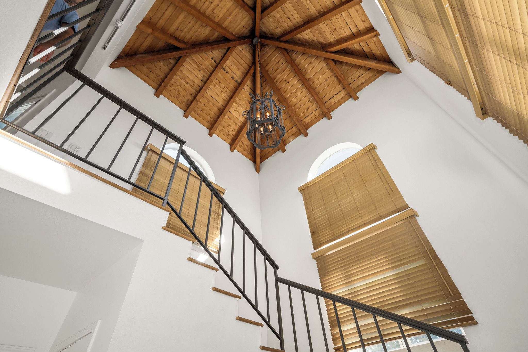 Un escalier en colimaçon avec des rampes et un plafond en bois.