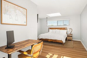 Ein Schlafzimmer mit einem Bett, einem Schreibtisch, einem Stuhl, einer Karte an der Wand und einem Fenster.
